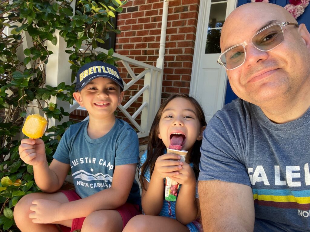 Craig, a colorectal cancer survivor, sitting with his two children on a porch.