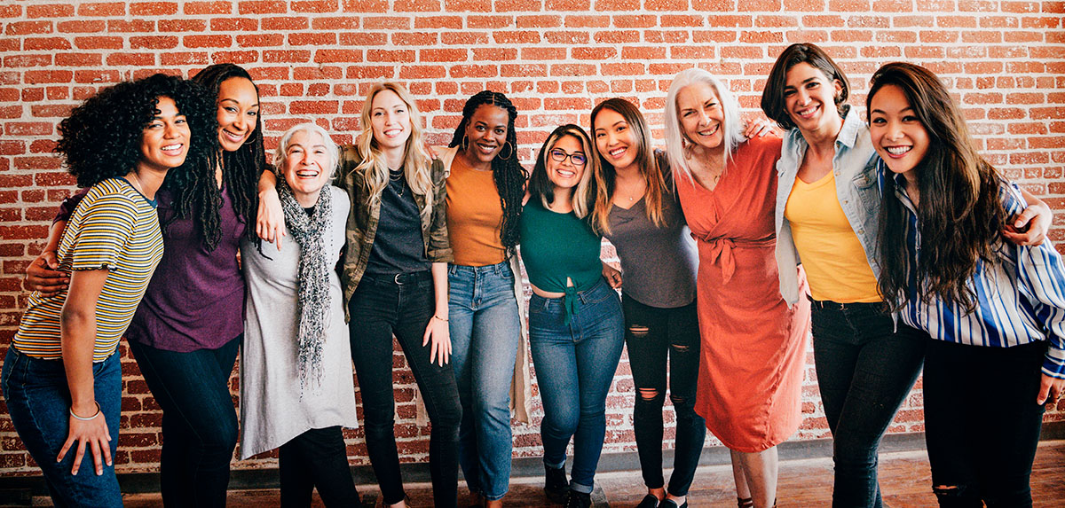 Diverse group of women in front of a brick wall smiling and laughing